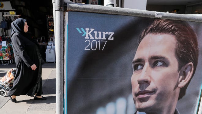A veiled woman passes an election poster of Austrian Foreign Minister Sebastian Kurz, the leader and top candidate of the Austrian Peoples Party in Vienna, Austria, Oct. 14, 2017. The Austrian federal elections will take place on Oct. 15, 2017.