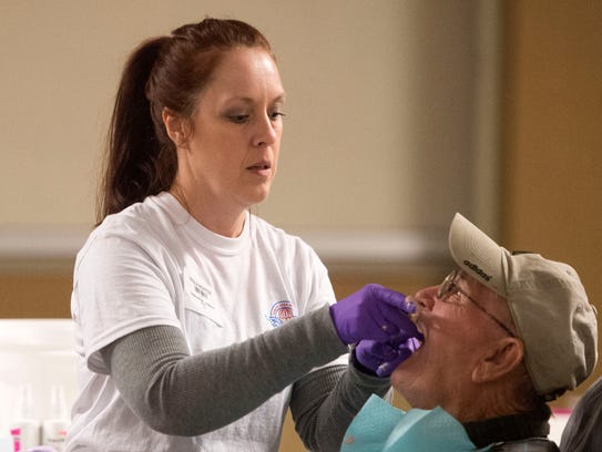 Dental Assistant Paula Nidiffer removes a mold from patient Robert Thompson's mouth at a Remote Area Medical mobile clinic in Chilhowee Park on Feb. 4, 2017. CAITIE MCMEKIN/NEWS SENTINEL