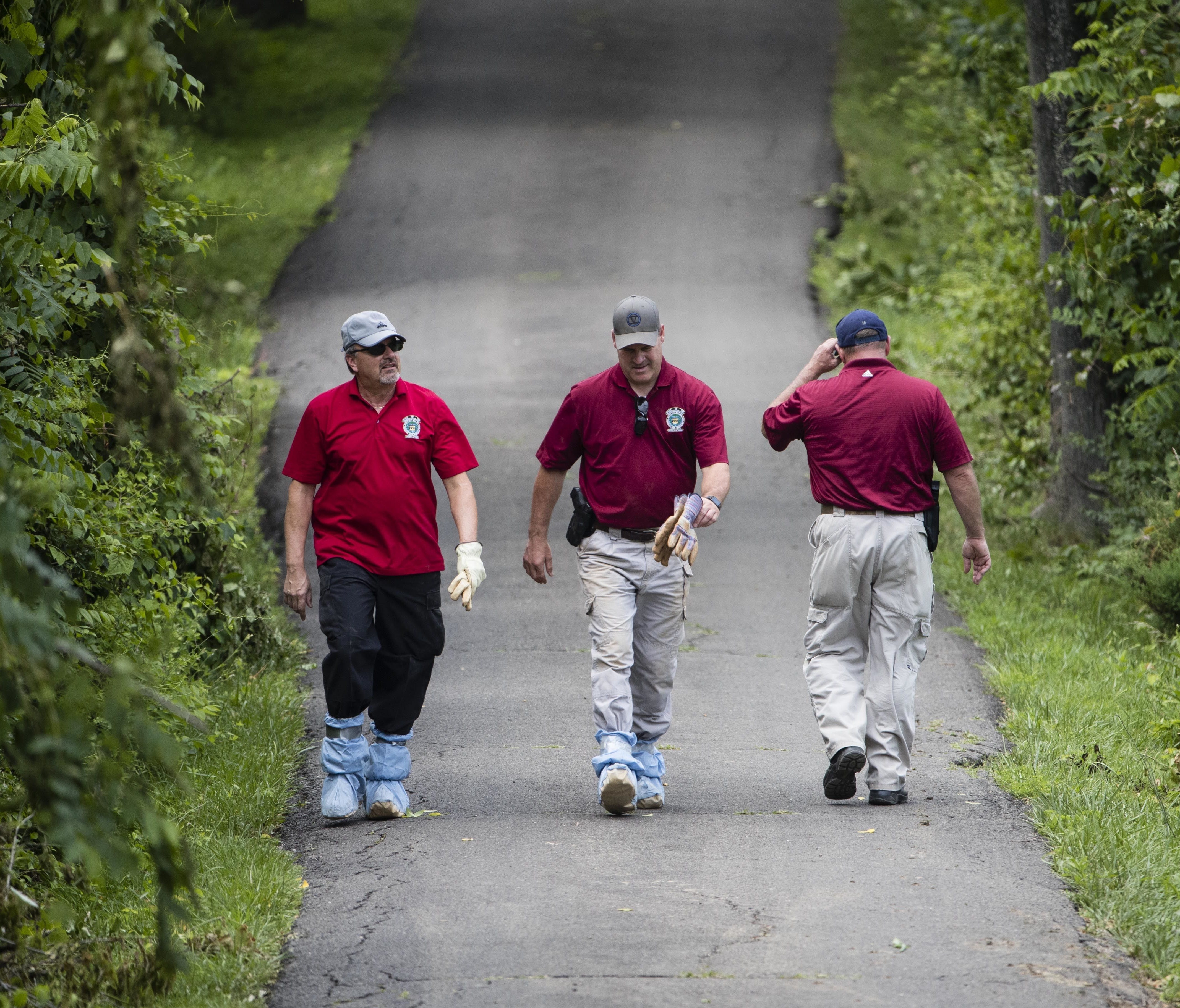 Investigators walk along a blocked off drive way in Solebury, Pa., during the search for four missing young Pennsylvania men feared to be the victims of foul play.