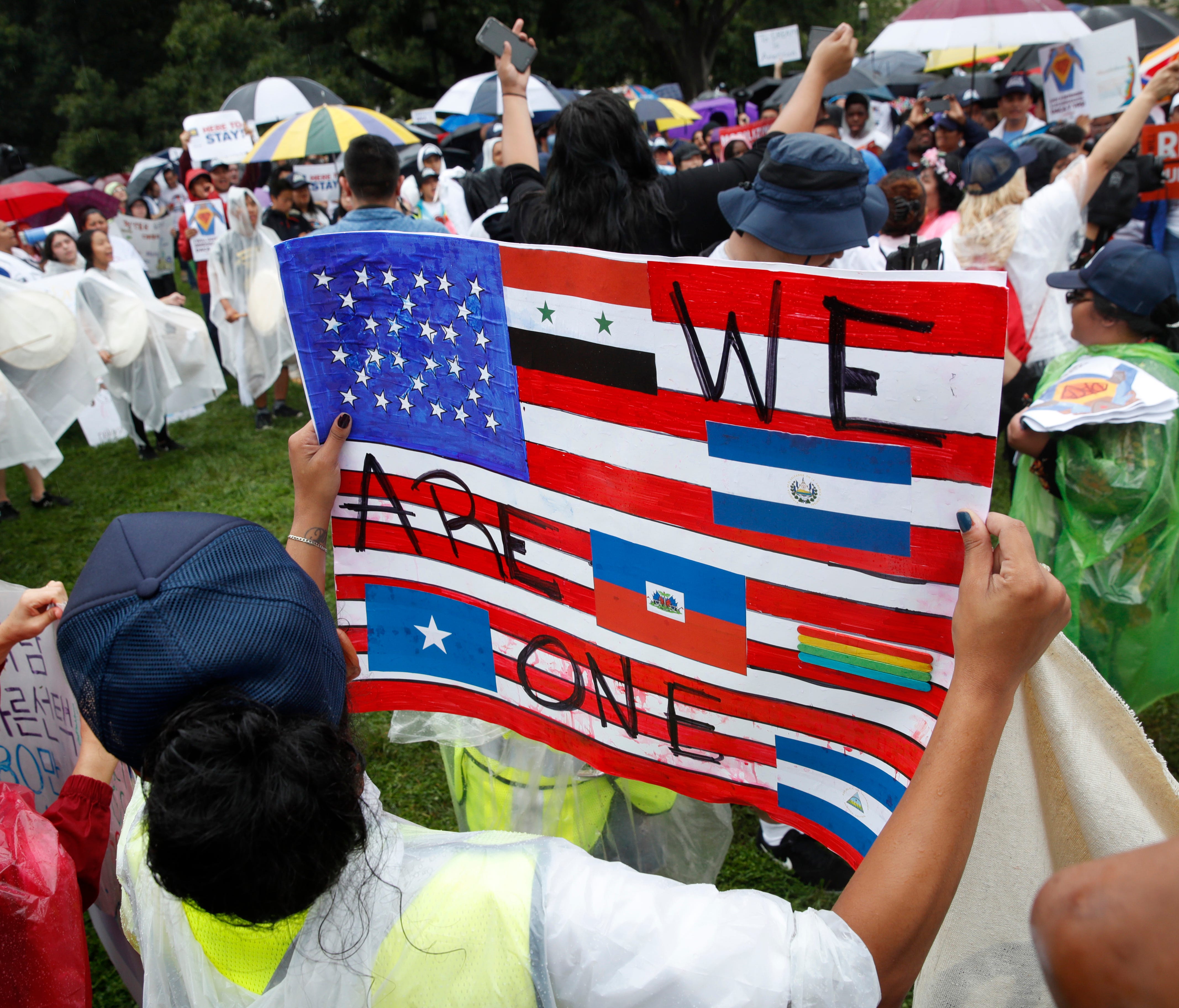A woman holds a sign declaring one nation of immigrants, during a rally in favor of DACA and immigration reform on Aug. 15, 2017, at the White House in Washington. The protesters want to preserve the Obama administration program known as Deferred Act