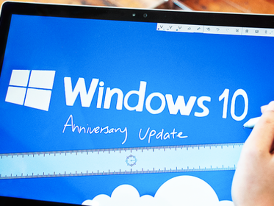 The Microsoft Windows 10 logo shown above the words Anniversary Update on a  Surface Tablet