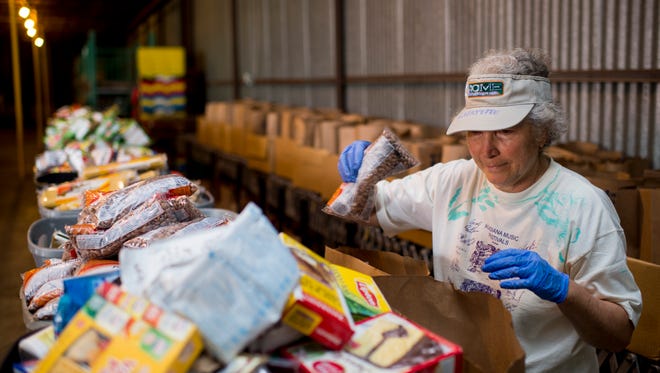 Volunteer Jane Rosen fills bags with food supplies at the FoodNet warehouse in Lafayette, LA, Wednesday, April 1, 2015. 