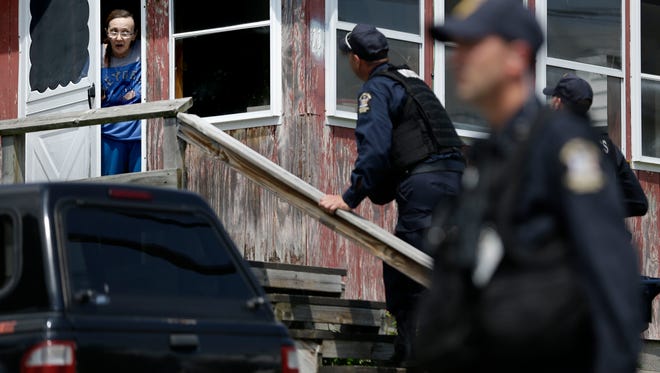 Law enforcement officers question a woman on June 10, 2015, who lives near a prison in Dannemora, N.Y., as they searched houses near the maximum-security prison where two killers escaped using power tools.