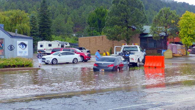 Storm water rushed onto Mescalero Trail off Sudderth Drive Friday in Ruidoso. The heavy downpour,apparently disguisied the depth of an area marked by an orange barricade. The car had to be pulled out of the deep water.