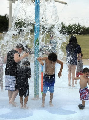 Kids stand under the water bucket to get splashed at the Nelson Park splash pad on Saturday, Aug. 1, 2015.