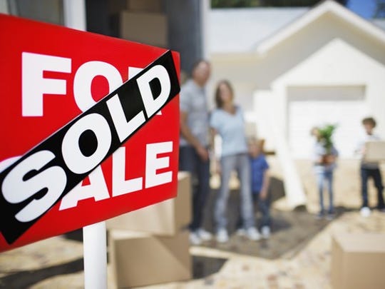 A family standing behind a for sale sign with a sold sign on it