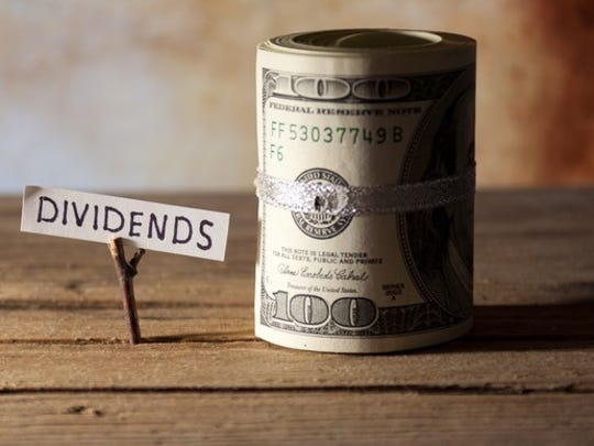 A roll of dollar bills beside a note saying dividends.