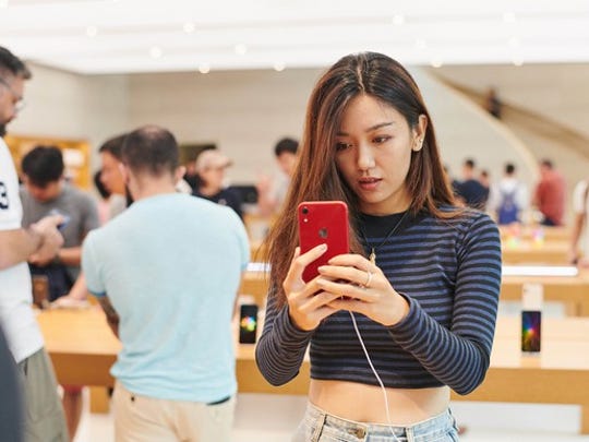 A woman looking at a red iPhone in an Apple store in Singapore.