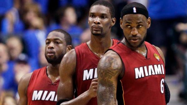 Miami Heat's Dwyane Wade, left, Chris Bosh, center,  and LeBron James look on during a break in the second half of Game 4 of the NBA Finals basketball game in Dallas.
