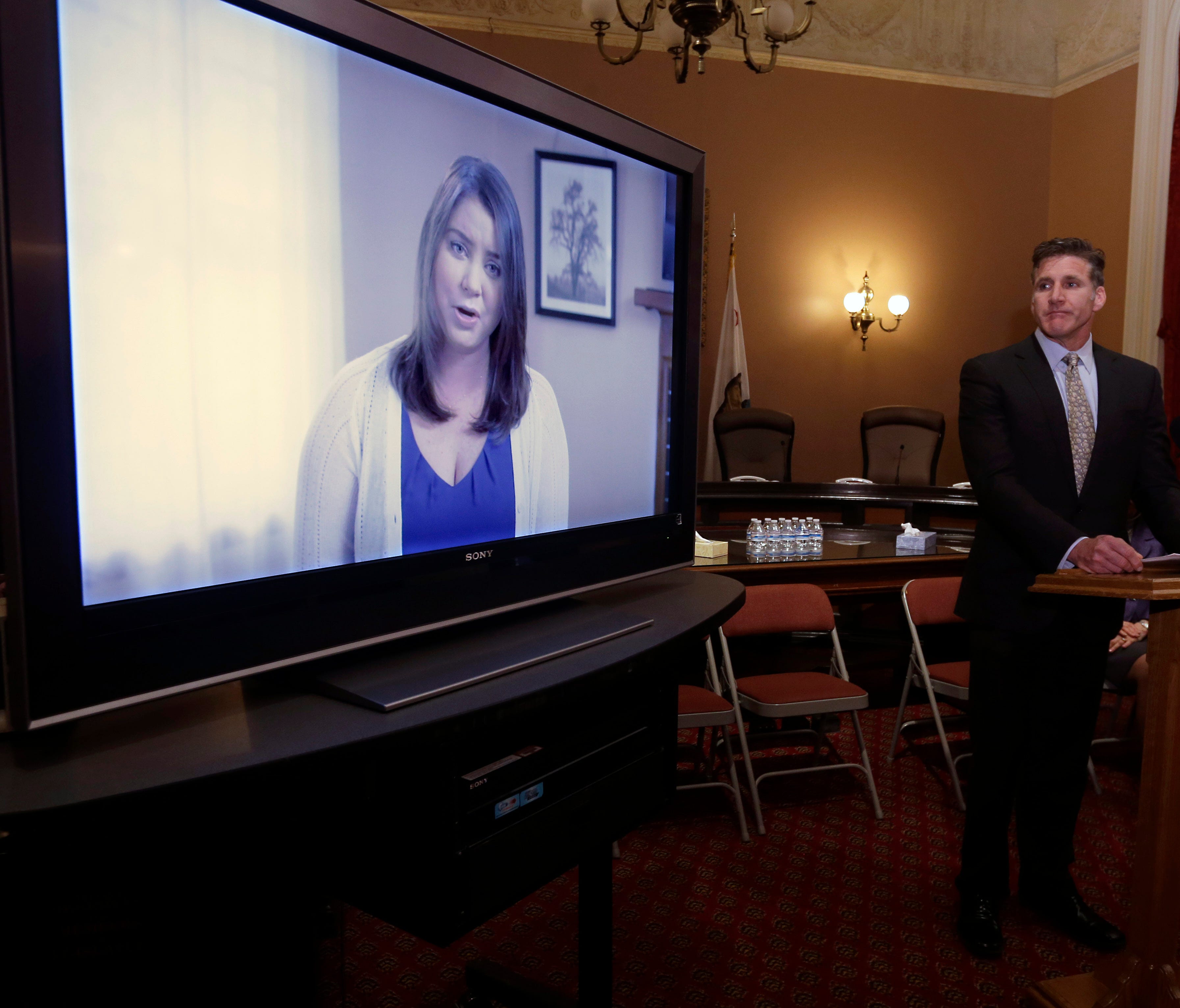 In this March 25, 2015 file photo, Dan Diaz, husband of Brittany Maynard, watches a video of his wife, recorded 19 days before her assisted suicide death during a news conference in Sacramento, Calif. In it, she says that she should not have to leave