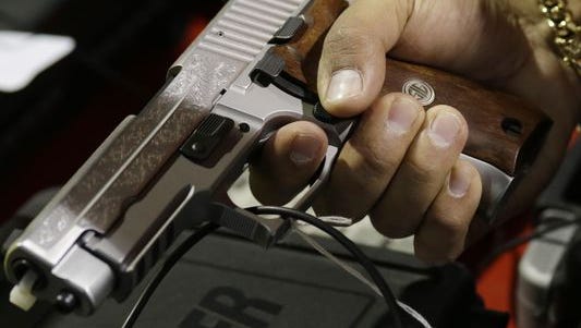 A customer looks at a SIG Sauer hand gun at a gun show held by Florida Gun Shows, Saturday, Jan. 9, 2016, in Miami. President Barack Obama announced proposals this week to tighten firearms sales through executive action.