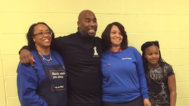 Former Piston Mateen Cleaves poses for a picture with volunteers at the second annual, 1 Goal, 1 Passion: Hope for the Holidays, initiative held at the Boys and Girls club on Detroit's east side on Friday, Dec. 12, 2014.