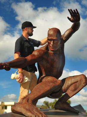 Chad Shores, the conservator and co-founder of Heritage Conservation, heats up the statue of Kelly Slater to apply a custom mix of wax to the metal. The weather, sun and salt affects the bronze in the statue, requiring conservation to the finish.