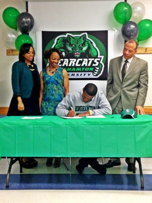 Binghamton University basketball player Marlon Beck signs his National Letter of Intent while flanked by his sister Melissa Beck (far left), his mother Yvonne Prettyman-Beck (left), and his father Marlon Beck at the Bowie Gym in Bowie, Md., in April 2013.