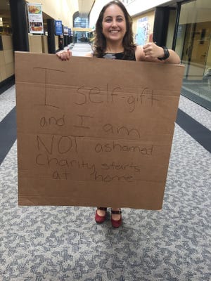 Ilana Kowarski, FLORIDA TODAY's retail and real estate reporter, is holding up a sign, which says, "I self-gift and I am not ashamed.