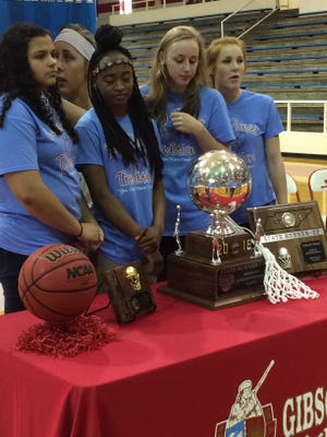 Gibson County girls basketball players Justyce White, Briana Fields, Erin Lannom and Allie Smithson prepare for photos with the TSSAA Class A runner-up trophy after supporters gathered at the school Sunday to celebrate the season.