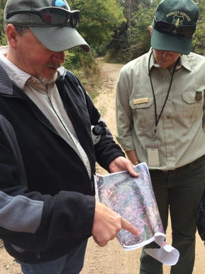 Shawn Martin, Silviculturist for Cibola National Forest's Sandia District, and Meckenzie Helmandollar, former acting public affairs officer for the Cibola National Forest look at an areal image of conifer stands.