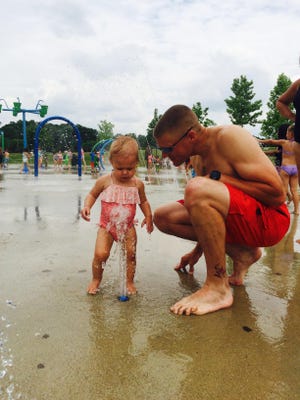 Joe Deppen of Farmington Hills helps daughter Isla, 14 months, cool off at the splash pad.