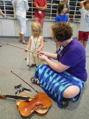Valerie Arsenault showing a camper a bow.
