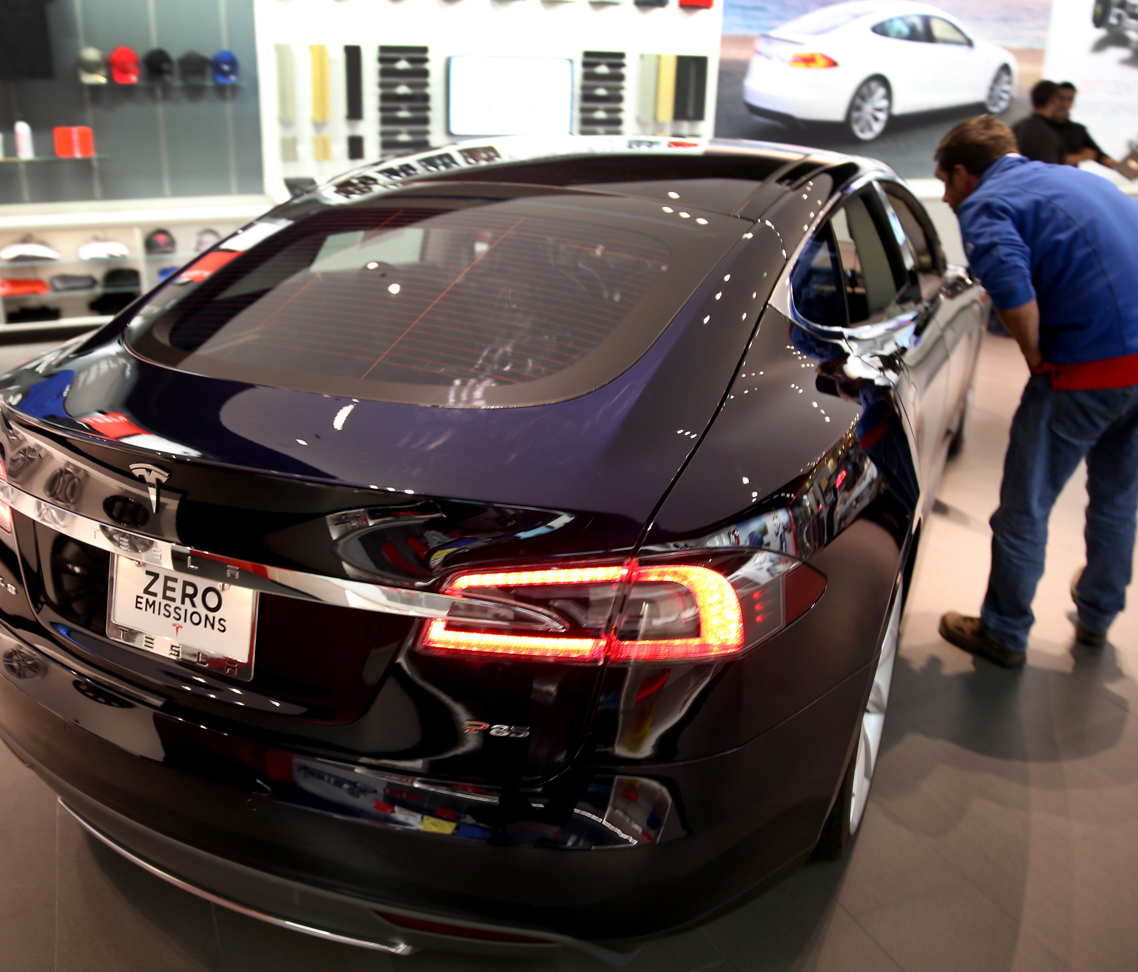 A visitor to theTesla Motors showroom looks at a vehicle at the Dadeland Mall in Miami in this 2014 file photo