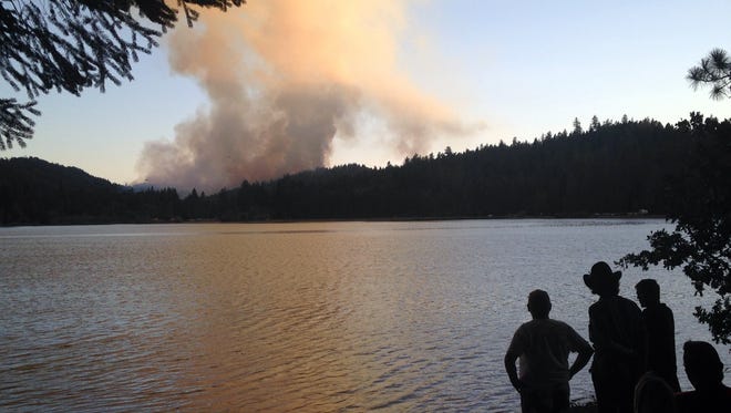 People gather on the shores of Lake Selmac near Selma, Ore., on Monday, July 28, 2014 to watch the Reeves Creek fire. The fire burned about 200 acres of drought-parched woods and threatened seven homes in a rural area about 15 miles southwest of Grants Pass, Ore. By Tuesday, a fire line was built around 70 percent of the fire, according to Oregon Department of Forestry. (AP Photo/Melissa McRobbie/The Grants Pass Daily Courier)