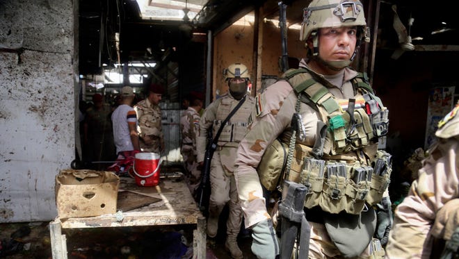 Security forces inspect the scene after a bomb explosion at an outdoor market in Baghdad's northern neighborhood of Shaab, Iraq, on May 17, 2016.