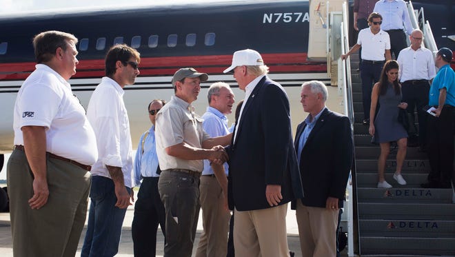 Republican presidential candidate Donald Trump, followed by his running mate, Indiana Gov. Mike Pence, shakes hands with Louisiana Attorney General Jeff Landry as he is greeted by Louisiana officials upon his arrival at the Baton Rouge airport in Baton Rouge, La., Friday, Aug. 19, 2016. (AP Photo/Max Becherer)