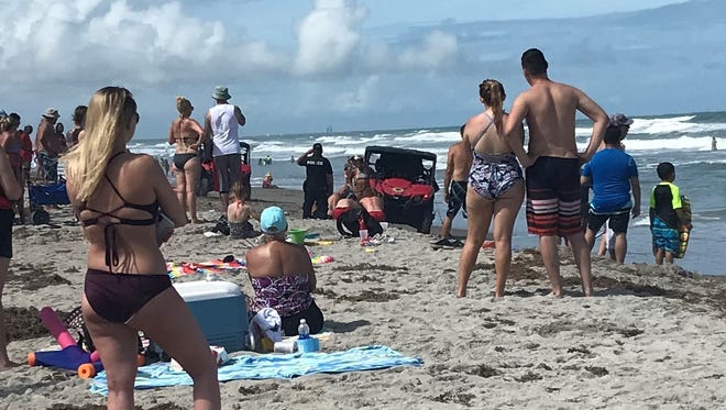 Lifeguards apply CPR to a woman who was pulled from a rip current near Lori Wilson Park in Cocoa Beach on Saturday.