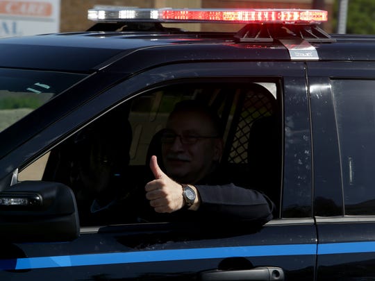 A police officer gives a thumbs-up to children lining the parade route during the 93rd Annual Dearborn Memorial Day Parade.