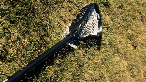 Lacrosse racket lying on grassy field, close-up
