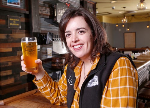 co-owner stacy grove hoists a pint of nolas golden