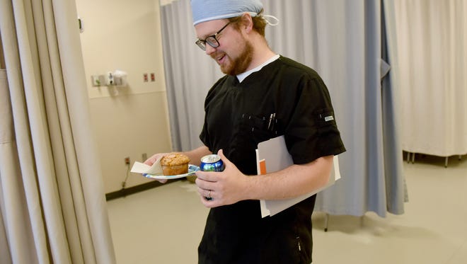 Gideon Carlisle, an RN at Vance Thompson Vision, brings a patient a muffin and a soda in the Surgery Center on April 12, 2017.