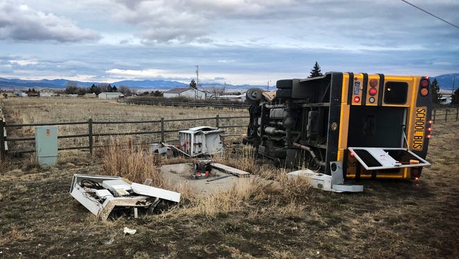 A school bus sits on its side Monday north of Helena after a crash. The Montana Highway Patrol says the Helena school bus driver pulled away from a stop sign into crossing traffic and the bus was hit by a pickup truck, causing it to go off the road and tip onto its side.