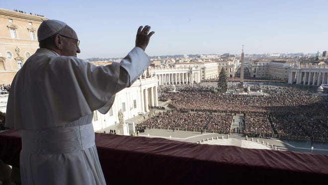 Pope Francis waves to faithful during his Christmas' day blessing from the main balcony of St. Peter's Basilica at the Vatican on Dec. 25, 2017.