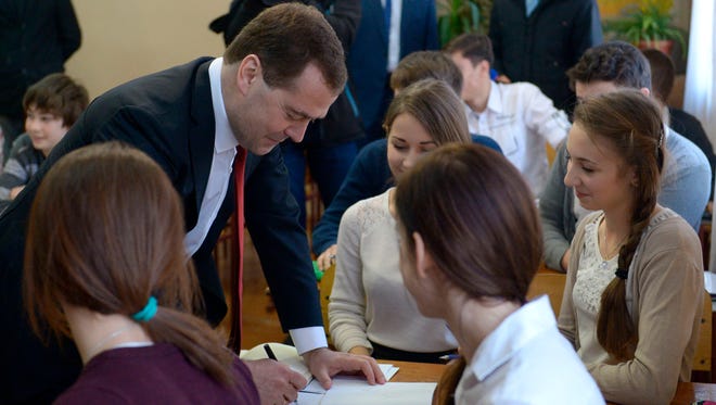 Russian Prime Minister Dmitry Medvedev, second left, speaks to school-children while visiting Crimea in Simferopol, Crimea, Monday, March 31, 2014. Russia's prime minister is visiting Crimea to consider priorities for its economic development following the Russian takeover. Dmitry Medvedev is leading a delegation of Cabinet ministers and is chairing a meeting Monday to discuss priorities for federal assistance to the region, which Russia annexed from Ukraine earlier this month. (AP Photo/RIA-Novosti, Alexander Astafyev, Government Press Service)