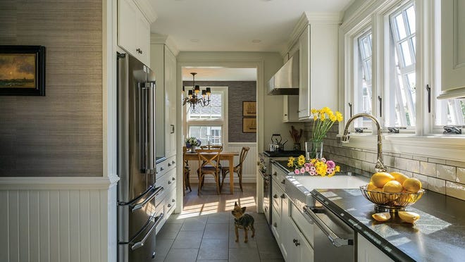 Dante the Yorkie surveys the new galley kitchen, which is outfitted with Medallion cabinets and soapstone counters; wallpaper from Serena & Lily.