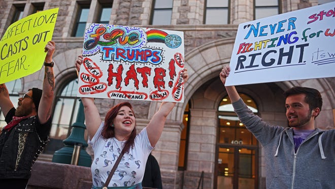 From left, Addison Avery, who organized the demonstration, Aliyah Kono and Adam Jorgensen, all of Sioux Falls, take part in a peaceful demonstration in response to Donald Trump's victory Wednesday, Nov. 9, 2016, in front of the Federal Courthouse in downtown Sioux Falls. 