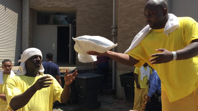 Inmates from Caddo Correctional Center unload sand bags at RiverView Hall and Theater.