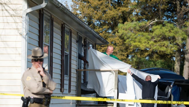 Sheets are held as a body is removed from a residence where police say seven children and one adult have been found dead Monday, April 6, 2015, in Princess Anne, Md.