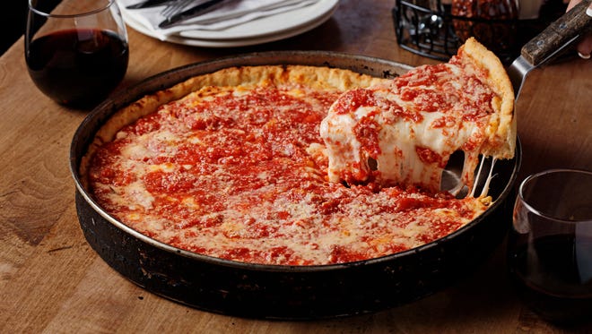 A slice of Lou Malnati’s famous deep dish pizza, being served piping hot, straight from the pan.