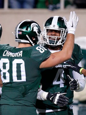 Michigan State's Malik McDowell (4) celebrates with Dylan Chmura after McDowell returned an interception for a touchdown against Penn State during the fourth quarter of an NCAA college football game, Saturday, Nov. 28, 2015, in East Lansing, Mich. Michigan State won 55-16.