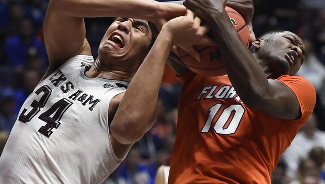 Texas A&M center Tyler Davis (34) and Florida Gators forward Dorian Finney-Smith (10) battle for the ball during the first half of the SEC Men's Basketball Tournament game at Bridgestone Arena, Friday, March 11, 2016, in Nashville, Tenn.