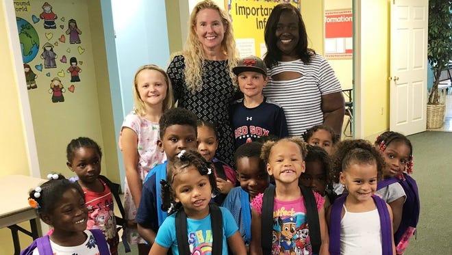 Kelly Decowski, her children Sarah and Tyler, Thelma Washington, executive director of Gertrude Walden Child Care Center, and some students enjoy colorful new backpacks donated by the Decowski family.