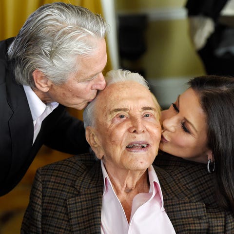 Actor Kirk Douglas, center, gets a kiss from his...