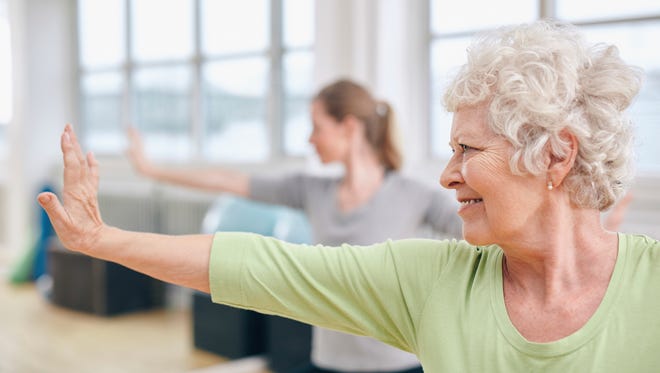 Senior woman doing stretching exercise at yoga class