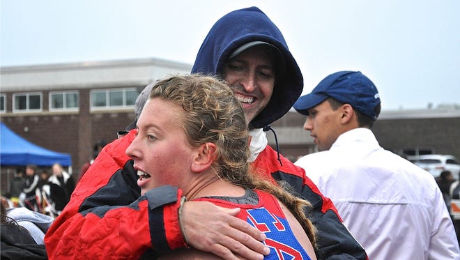 Carmel coach Eric Schwark embraces freshman Jessica Kozma after she anchored the winning girls 4x1,600 team..