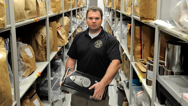 Ryan Dott, forensic specialist, holds a safe that is evidence in the crime lab at the Law Enforcement Center. The city's auditor has recommended the police department look into opening a bank account for the cash it seizes from crime scenes or lost property cases.