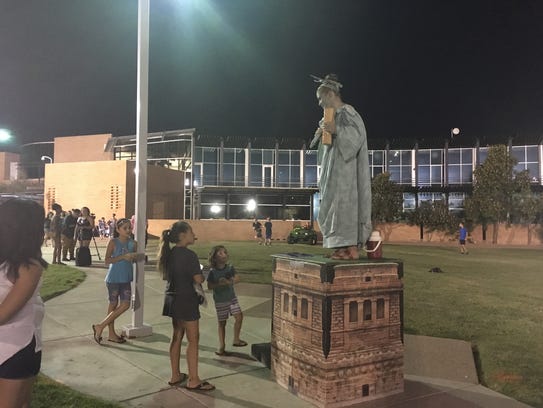 Several children look up at the Statue of Liberty,