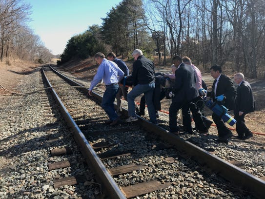 Sen. Bill Cassidy, R-La., (second to the right) helps others transport an injured person after a train crash in Virginia.