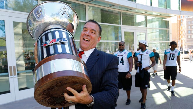 Arizona Rattlers President Joe Windham carries the championship trophy to US Airways Center following the team's victory parade on Wednesday, Aug. 27, 2014 in Phoenix.